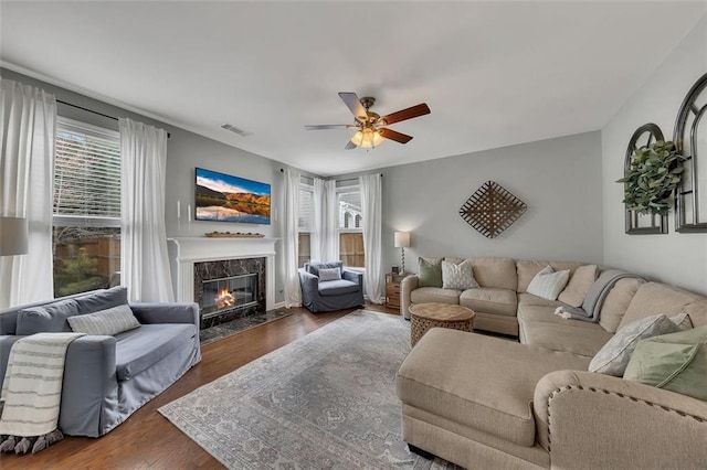 living room featuring dark wood-style floors, a premium fireplace, visible vents, and a wealth of natural light