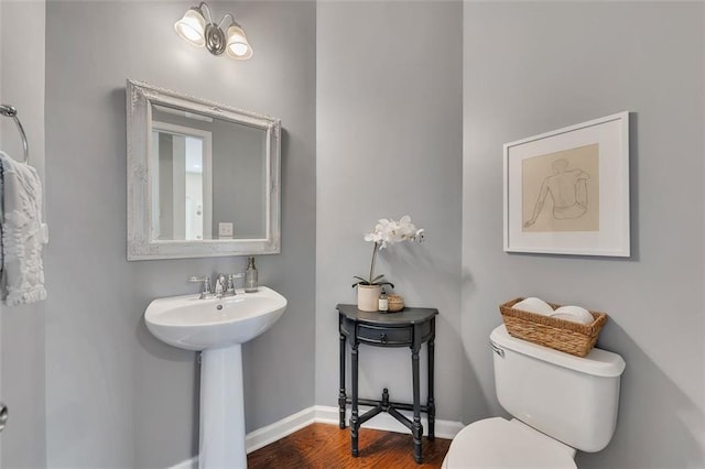 bathroom featuring baseboards, a sink, toilet, and wood finished floors