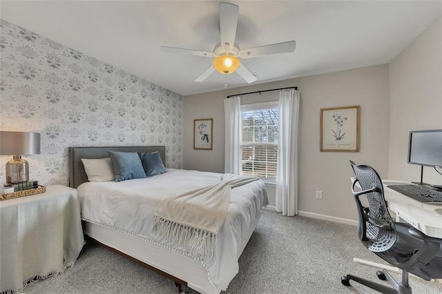 bedroom featuring ceiling fan, light colored carpet, an accent wall, baseboards, and wallpapered walls