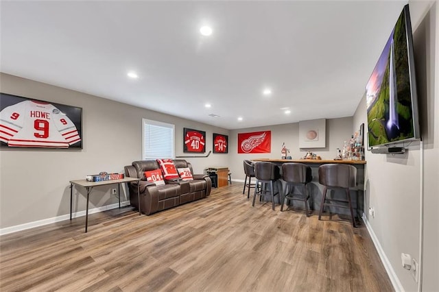 living room featuring baseboards, a bar, wood finished floors, and recessed lighting