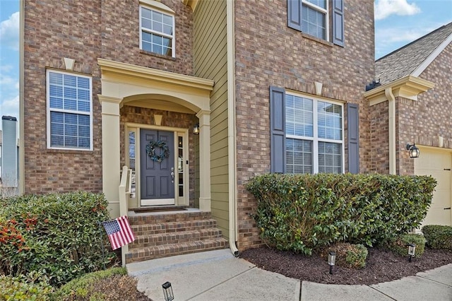 entrance to property featuring a garage and brick siding