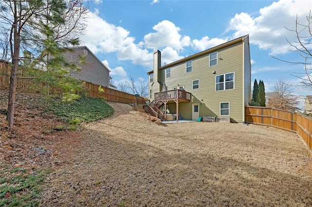 back of house with a deck, a chimney, a fenced backyard, and stairs