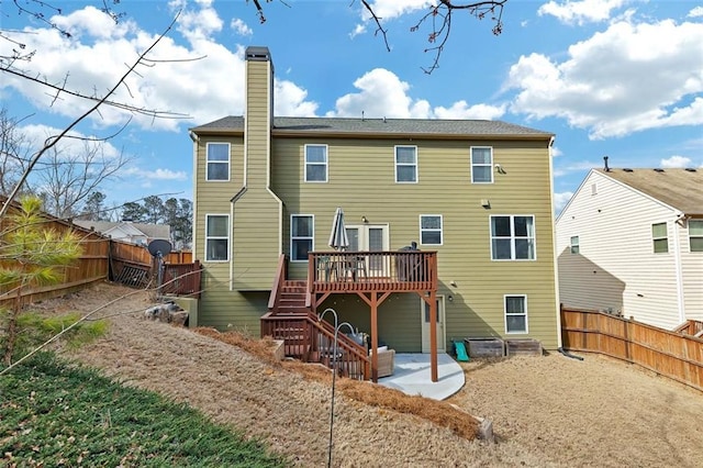 rear view of house featuring a fenced backyard, stairs, a chimney, and a wooden deck