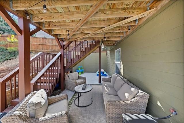 view of patio featuring fence, stairway, and an outdoor hangout area