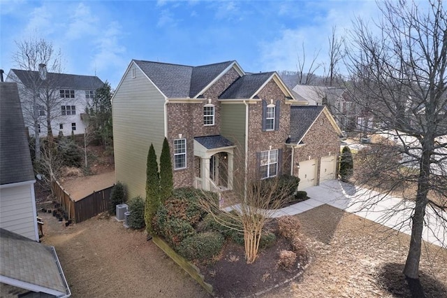 view of front of house featuring central AC unit, an attached garage, brick siding, a shingled roof, and concrete driveway