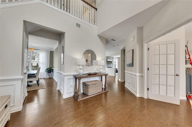 entryway featuring a wainscoted wall, wood finished floors, visible vents, and a decorative wall