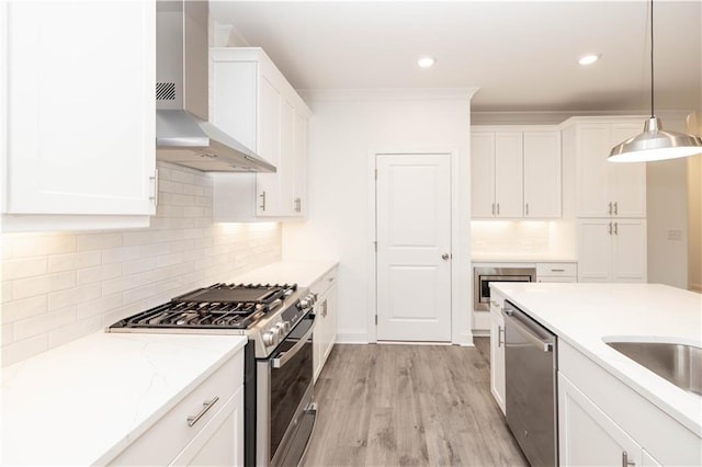 706 Dodd Ln Unit 157, Buford, GA 30518 - kitchen with appliances with stainless steel finishes, wall chimney range hood, white cabinetry, decorative light fixtures, and decorative backsplash
