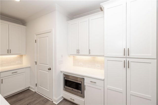 706 Dodd Ln Unit 157, Buford, GA 30518 - kitchen featuring stainless steel microwave, white cabinetry, tasteful backsplash, wood finished floors, and crown molding