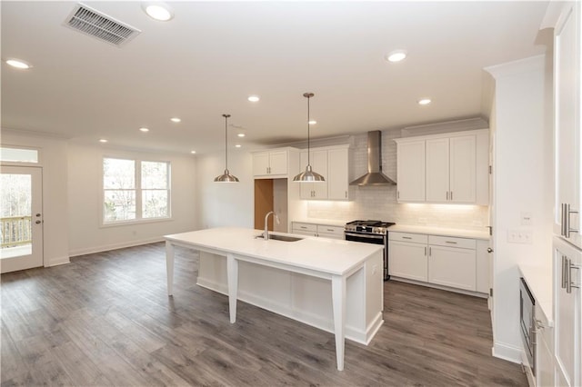 706 Dodd Ln Unit 157, Buford, GA 30518 - kitchen with wall chimney range hood, stainless steel range with gas cooktop, a sink, tasteful backsplash, and a kitchen island with sink