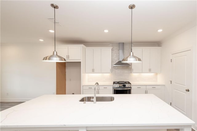 706 Dodd Ln Unit 157, Buford, GA 30518 - kitchen featuring gas stove, a sink, wall chimney exhaust hood, a kitchen island with sink, and white cabinetry