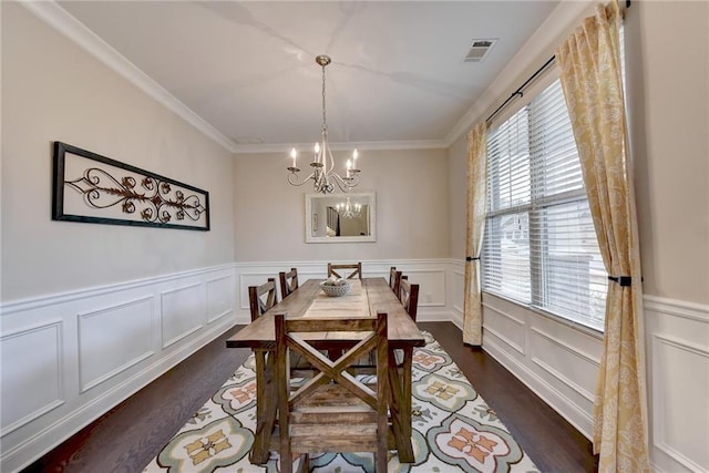 dining space featuring dark wood-type flooring, a notable chandelier, and crown molding