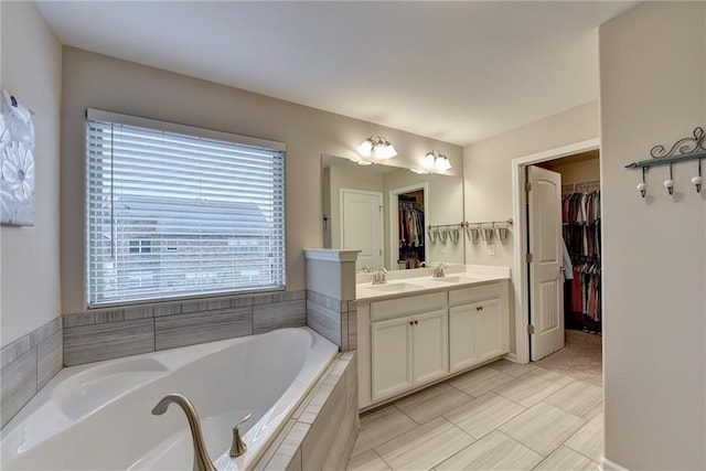 bathroom featuring vanity, tiled bath, and tile patterned flooring