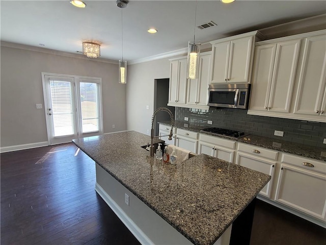 kitchen featuring a center island with sink, black gas stovetop, dark stone counters, dark hardwood / wood-style floors, and sink