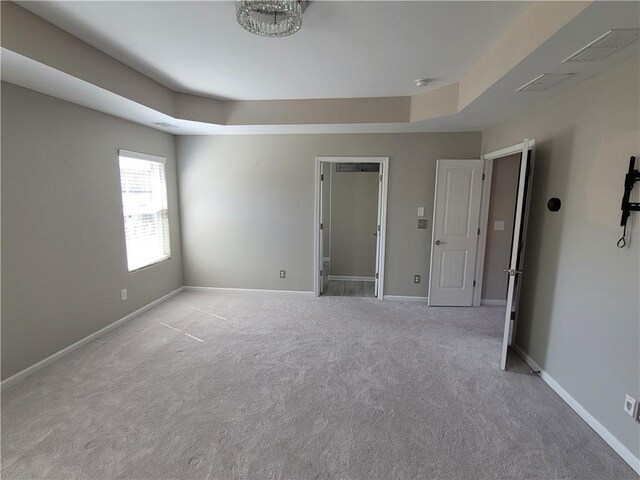 unfurnished bedroom with a raised ceiling and light colored carpet