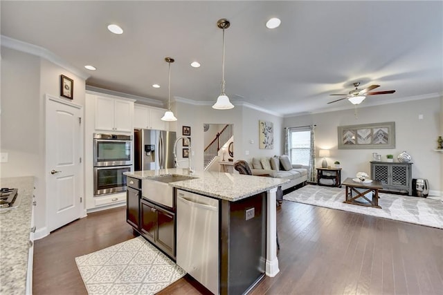 kitchen featuring a kitchen island with sink, hanging light fixtures, sink, white cabinets, and appliances with stainless steel finishes