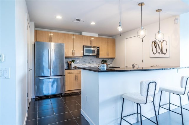 kitchen featuring pendant lighting, tasteful backsplash, a kitchen bar, kitchen peninsula, and stainless steel appliances