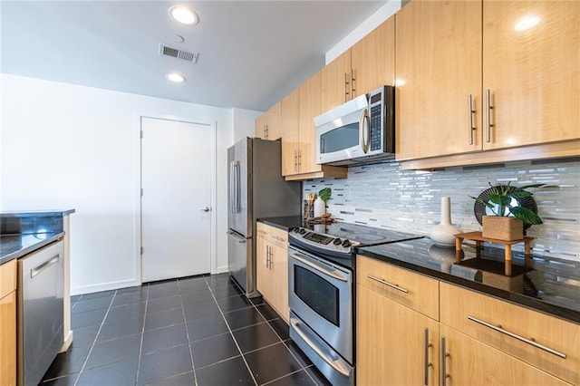 kitchen with light brown cabinetry, stainless steel appliances, dark tile patterned flooring, and tasteful backsplash