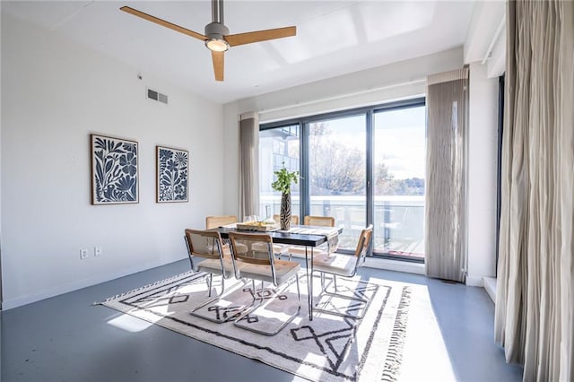 dining room with ceiling fan and concrete flooring