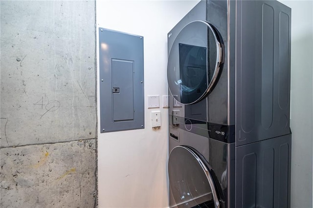 laundry area with electric panel and stacked washer / dryer