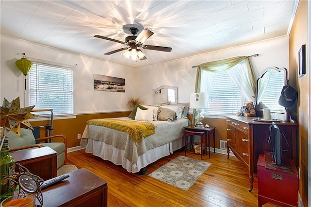 bedroom with visible vents, baseboards, ceiling fan, and wood finished floors