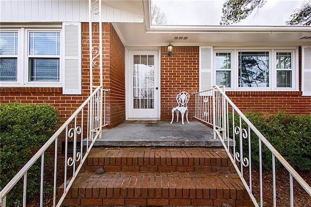 property entrance with brick siding and visible vents