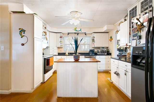 kitchen with a center island, appliances with stainless steel finishes, light wood-style floors, white cabinetry, and open shelves