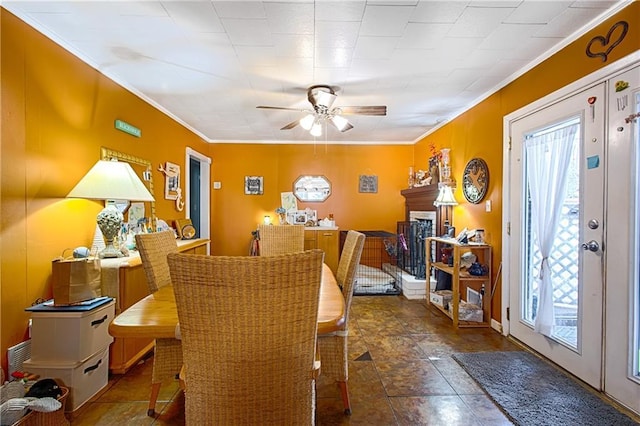 dining space with ceiling fan, a fireplace, and ornamental molding