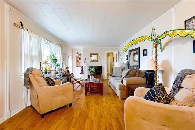 living area with crown molding and light wood-style floors