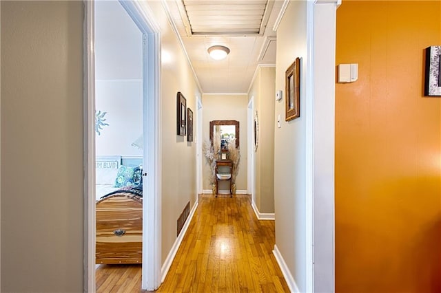 hallway with visible vents, crown molding, baseboards, and wood finished floors