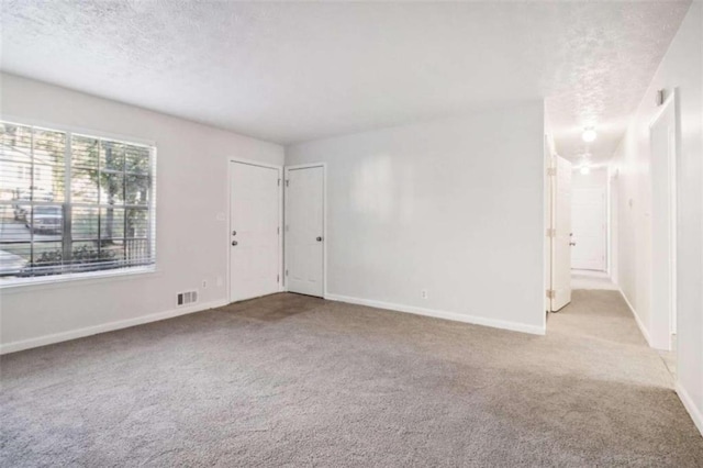 carpeted empty room with a textured ceiling