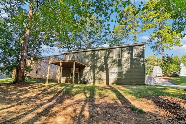 rear view of house with a lawn and a wooden deck