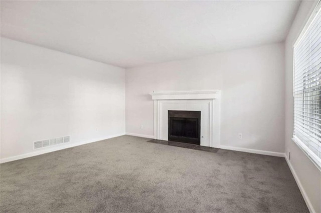 unfurnished living room featuring carpet flooring and plenty of natural light