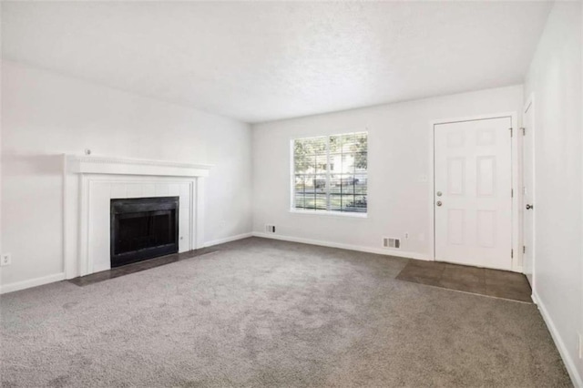 unfurnished living room with a tiled fireplace and dark colored carpet