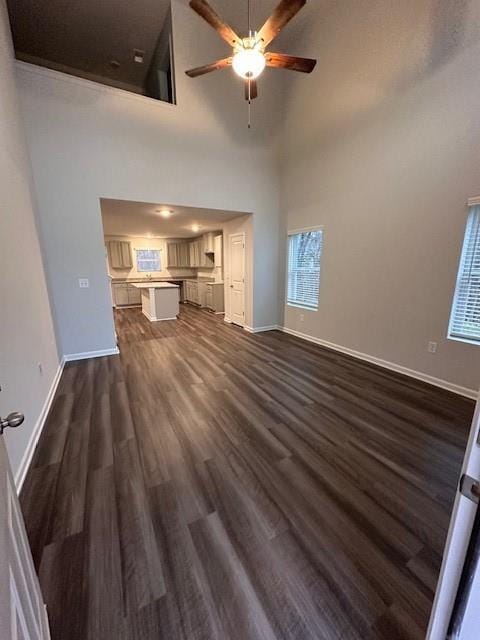 30 Barton Ln, Covington, GA 30016 - unfurnished living room featuring a ceiling fan, dark wood-type flooring, baseboards, and a towering ceiling
