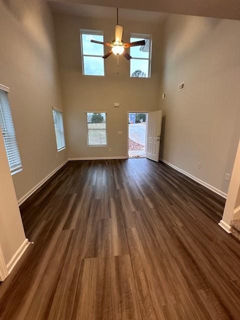 30 Barton Ln, Covington, GA 30016 - unfurnished living room featuring dark wood-style floors, a ceiling fan, baseboards, and a high ceiling