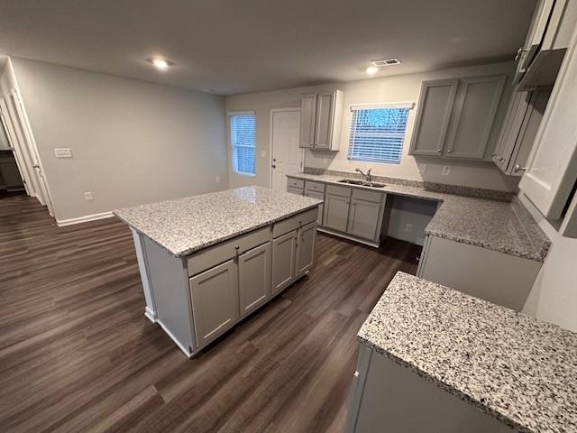 30 Barton Ln, Covington, GA 30016 - kitchen featuring gray cabinets, a sink, dark wood-style flooring, a center island, and light stone countertops