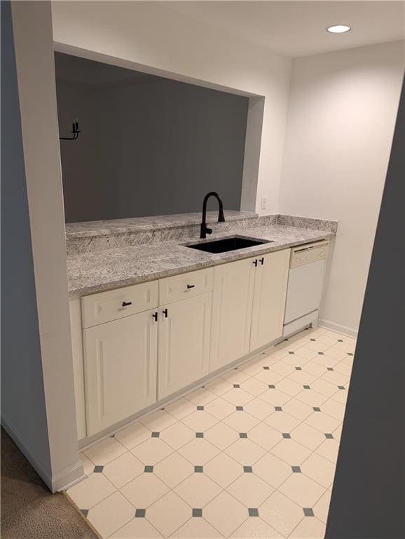 kitchen with white dishwasher, light stone counters, and sink