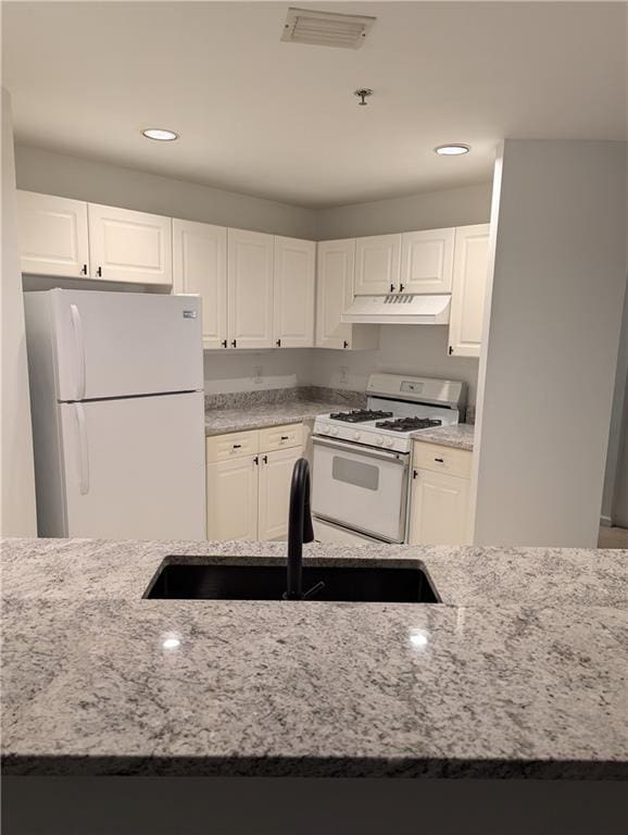 kitchen featuring light stone counters, sink, white cabinets, and white appliances