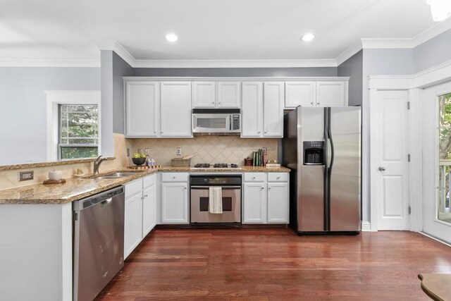kitchen featuring light stone countertops, white cabinetry, a sink, appliances with stainless steel finishes, and a wealth of natural light
