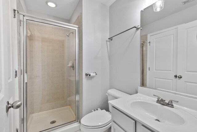 full bathroom featuring vanity, visible vents, toilet, and a shower stall