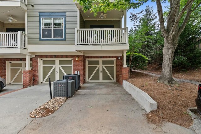 exterior space with brick siding, an attached garage, driveway, and a balcony