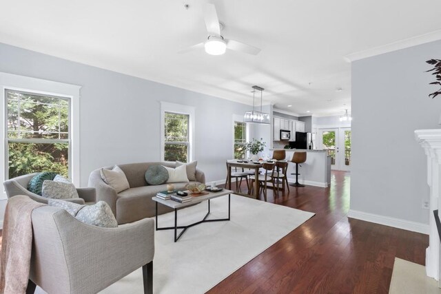 living area with dark wood-type flooring, a ceiling fan, and baseboards