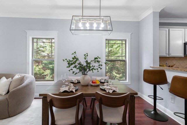 dining room with plenty of natural light, baseboards, crown molding, and wood finished floors