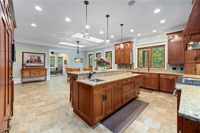 1447 Travis Smith Rd, Clarkesville, GA 30523 - kitchen with stone tile flooring, a sink, a kitchen island with sink, ornamental molding, and brown cabinets