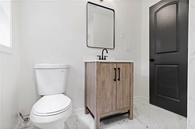 half bathroom with marble finish floor, baseboards, vanity, and toilet