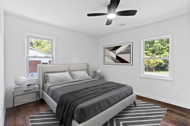 bedroom featuring dark wood-style floors, baseboards, visible vents, and ceiling fan