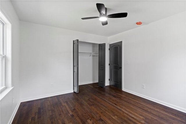 unfurnished bedroom with dark wood-type flooring, a closet, ceiling fan, and baseboards