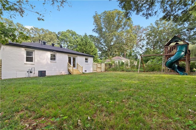 view of yard with entry steps, a playground, fence, and central AC