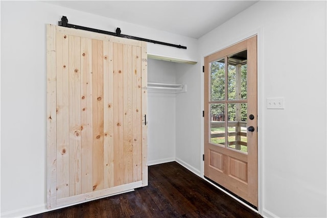 interior space with dark wood-style floors, baseboards, and a barn door