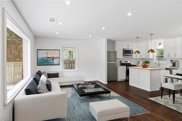 living area featuring a healthy amount of sunlight, dark wood-style floors, visible vents, and recessed lighting